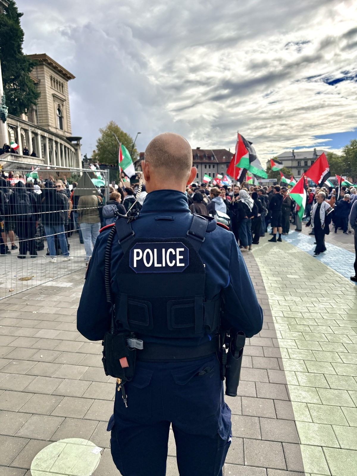 Un policier lausannois observe à distance la foule qui s'est réunie le samedi 10 octobre 2026 sur la place de la Riponne, à l'appel d'une marche pour la Palestine.