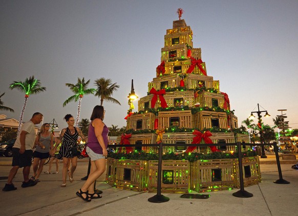 In this photo provided by the Florida Keys News Bureau, people walk past a stylized Christmas tree created from lobster traps Wednesday, Dec. 14, 2022, in Key West, Fla. The display is one of several  ...