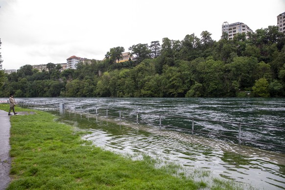 Un homme marche sur les berges du Rhone inondees suite a la montee du niveau des eaux du Rhone lors de fortes precipitations de pluies, ce jeudi 15 juillet 2021 a Geneve. (KEYSTONE/Salvatore Di Nolfi)