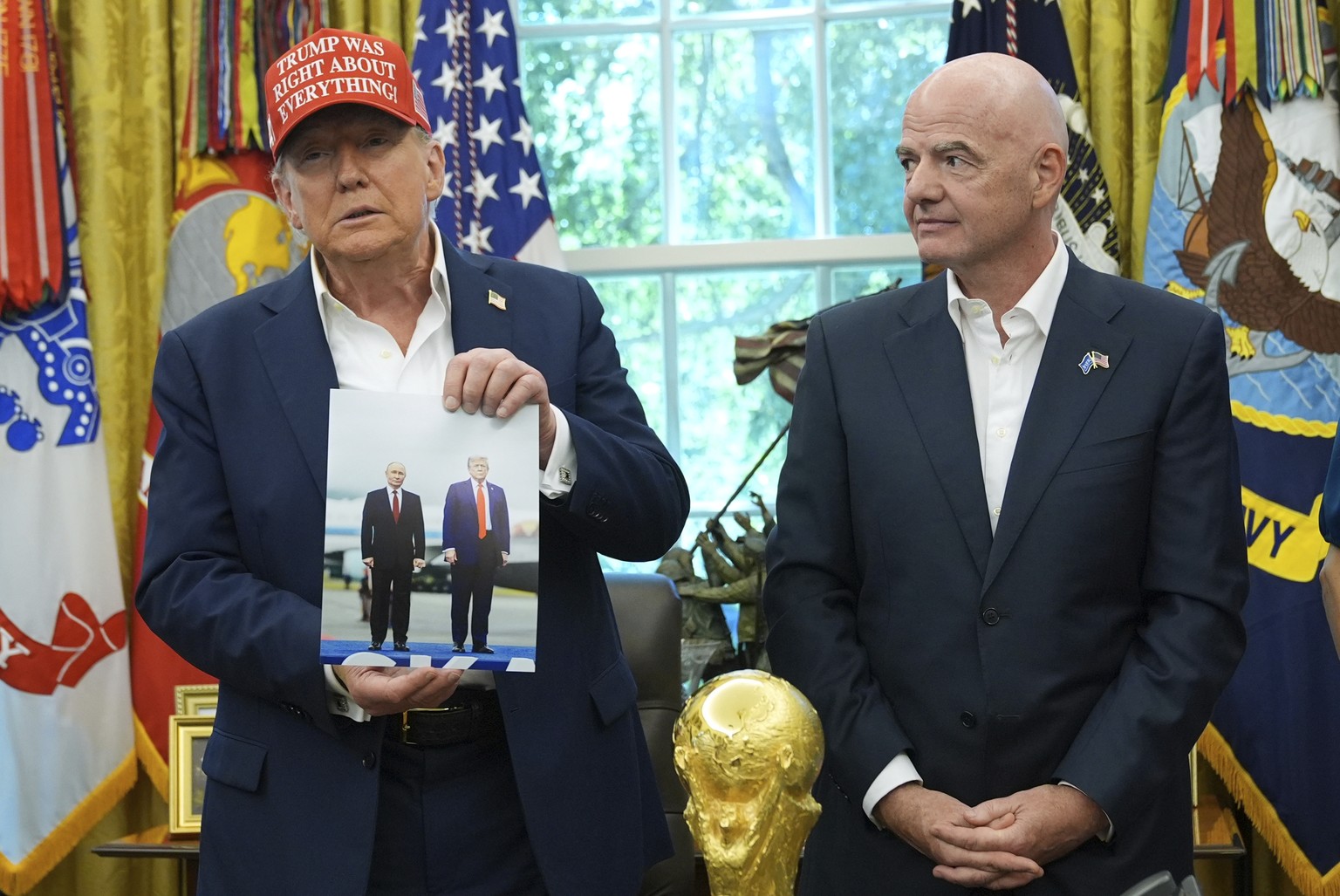 KEYPIX - President Donald Trump holds a photo of himself with Russian President Vladimir Putin as FIFA President Gianni Infantino watches during an announcement in the Oval Office of the White House,  ...