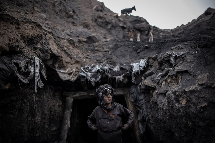 In front of the entrance stands a young boy who works in an informal coal mine in Chinarak.  Hundreds of miners, including children as young as ten and men over sixty, toil every day for a few cents.  Tunnel co...
