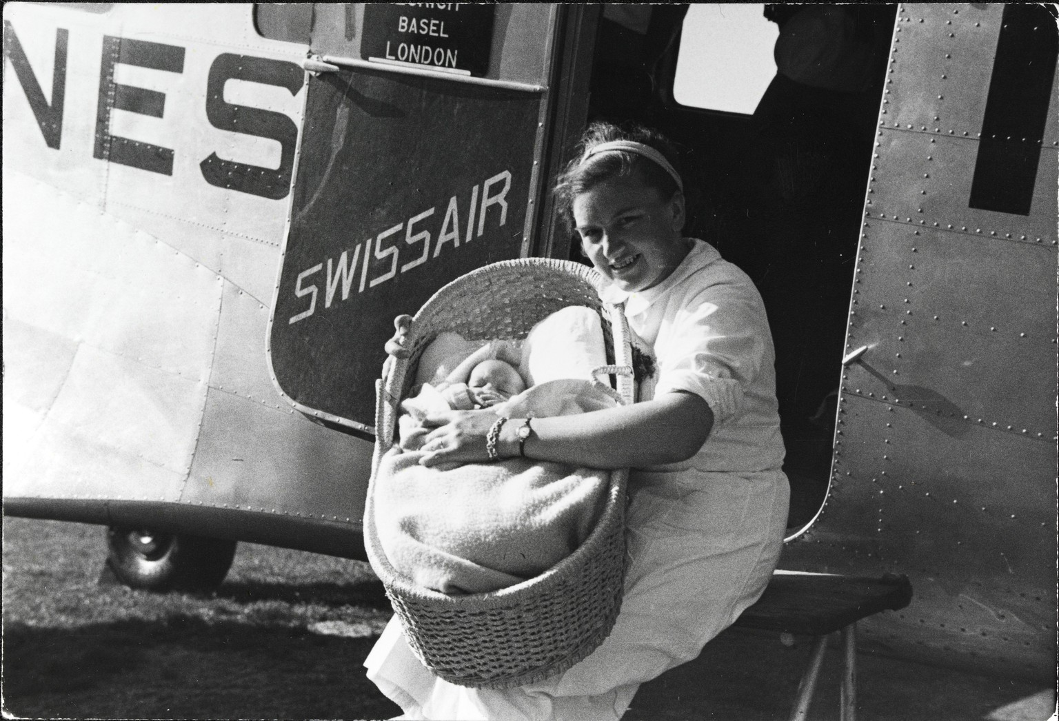 Eine Hostess der Swissair mit Baby vor dem Flug von Basel nach London zwischen&nbsp;1941 und 1950.