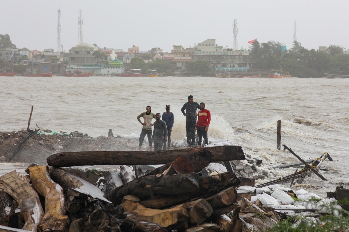 epa10691962 People stand on sandbags and debris as the sea water enters the low lying area near the sea coast in Mandvi, in the Kutch district of the western state of Gujarat, India, 15 June 2023. Vis ...
