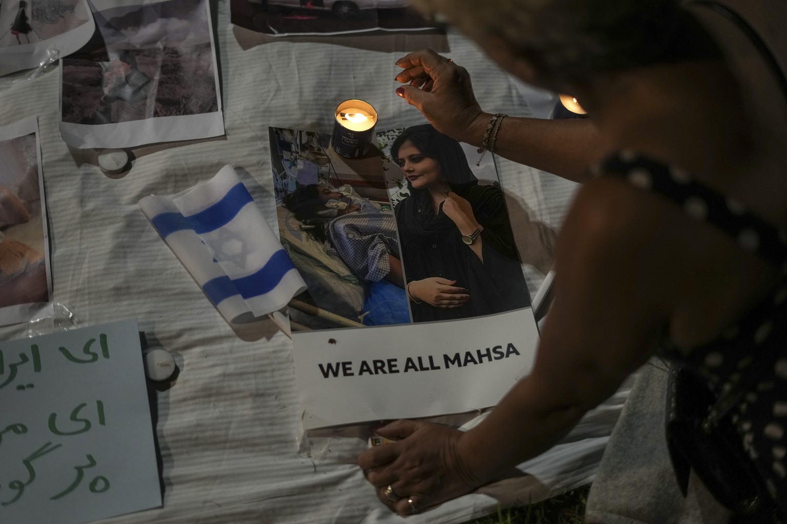 A woman lights a candle in solidarity with Iranian women during a protest against the death of Mahsa Amini, a woman who died while in police custody in Iran, during a rally in Tel Aviv, Saturday, Oct. ...