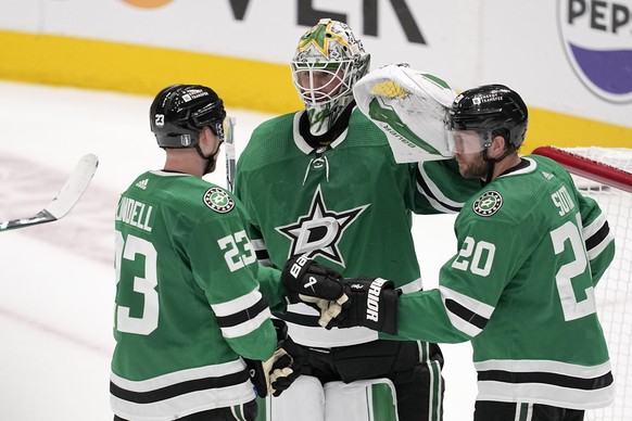 Dallas Stars' Esa Lindell (23), Jake Oettinger, center, and Ryan Suter (20) celebrate after a win over the Edmonton Oilers in Game 2 of the Western Conference finals in the NHL hockey Stanley Cup ...