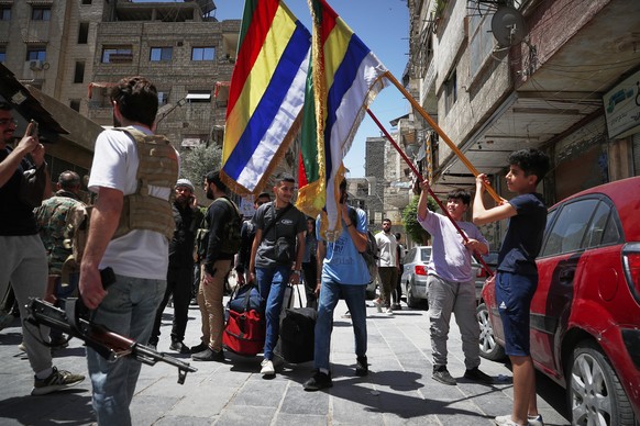 Druze boys hold their sect religious flags stand next to Druze gunmen, a day after clashes between members of the minority Druze sect and pro-government fighters left at least four people dead in the  ...