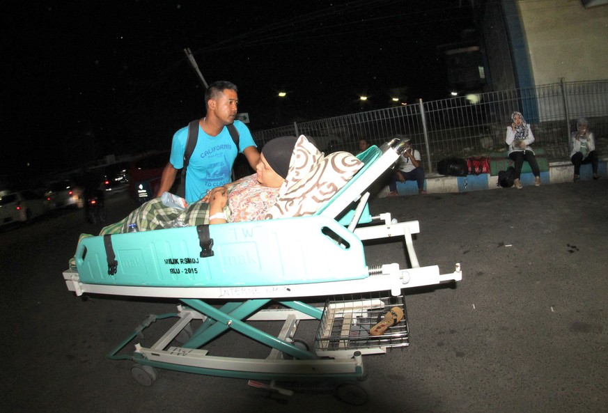 Ein Indonesier schiebt seinen verletzten Verwandten ins Krankenhaus.