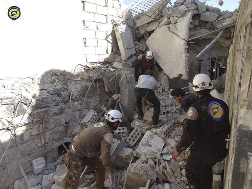 In this photo provided by the Syrian Civil Defense group known as the White Helmets, Syrian Civil Defense workers search through the rubble after airstrikes in the village of Hass in the Idlib provinc ...