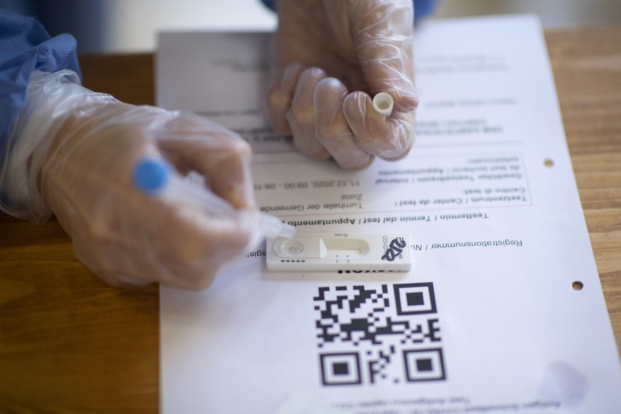 epa08876672 Medical staff takes a Covid-19 quick test during Covid-19 mass testing, in Zuoz, Switzerland, 11 December 2020. Three regions in the canton of Grisons will be mass tested during three days ...