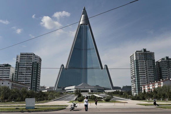 A traffic policeman is dwarfed by the 105-story Ryugyong Hotel in Pyongyang, North Korea, Wednesday, Sept. 11, 2019. Construction of the pyramid-shaped hotel, the capital city's most conspicuous ...