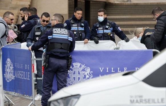 Police officers hide a dead body after a knife attack, outside the Marseille town hall, southern France, Saturday, March 12, 2022. A Frenchman with a knife injured three police officers in the souther ...