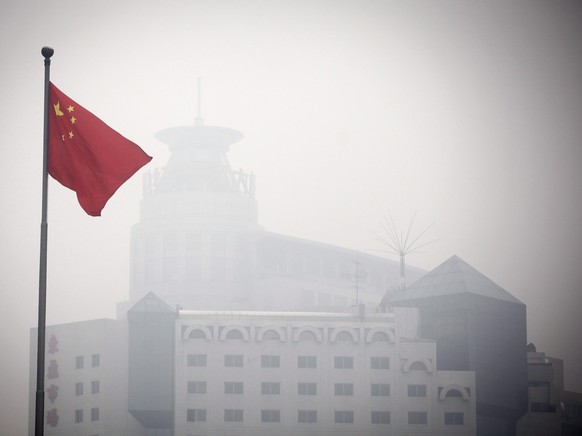 epa03022451 The Chinese national flag flames in front of a building barely visible due to heavy smog in Beijing, China, 02 December 2011. As the Climate Change Summit aimed at cutting global carbon em ...