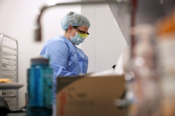 A worker looks at objects in a Defense POW/MIA Accounting Agency lab at Offutt Air Force Base, Monday, May 20, 2024, in Bellevue, Neb. Generations of American families have grown up without ever knowi ...