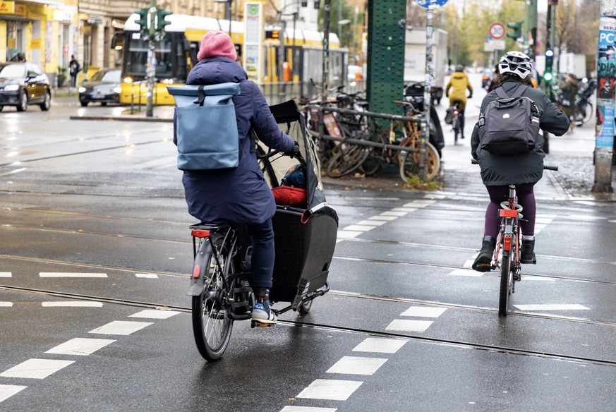 Links im Bild fährt eine Frau ein Cargobike.