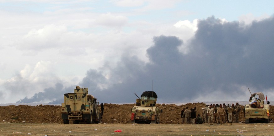 Irakische Soldaten beobachten, wie schwarzer Rauch aus dem brennenden Ajil-Ölfeld östlich von Tikrit aufsteigt. Teilweise zündeten die Terroristen die Ölfelder vor ihrem Rückzug selbst an.