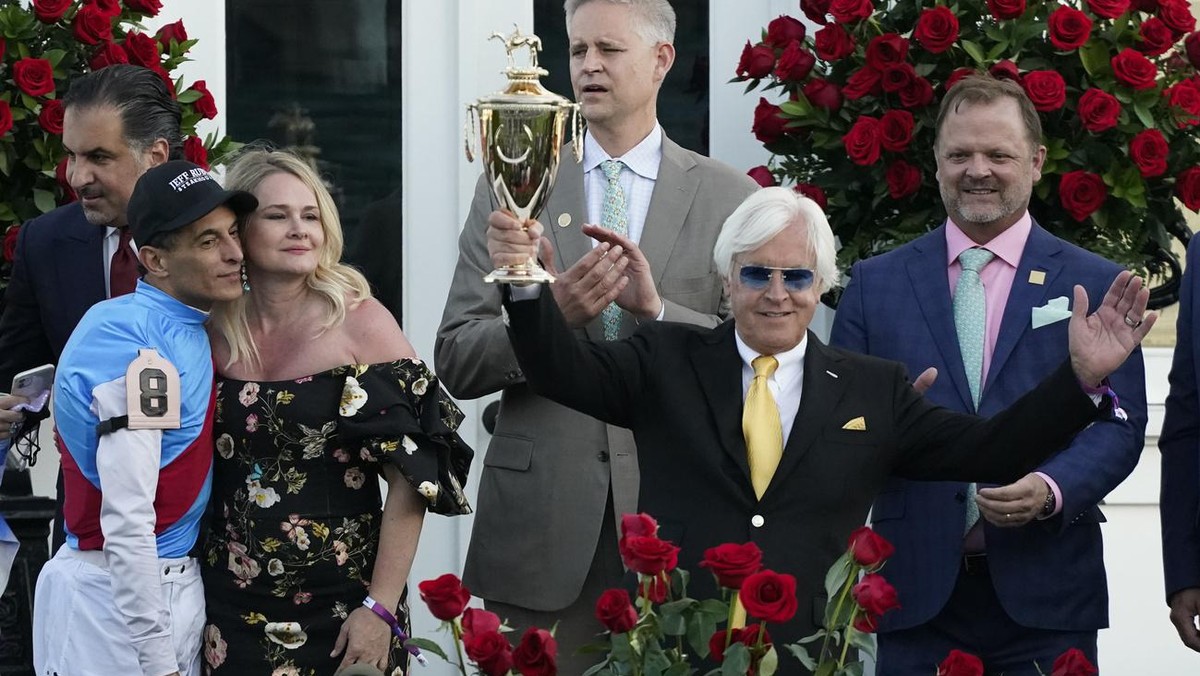 Jockey John Velazquez, left, watches as trainer Bob Baffert holds up the winner's trophy after they victory with Medina Spirit in the 147th running of the Kentucky Derby at Churchill Downs, Satur ...