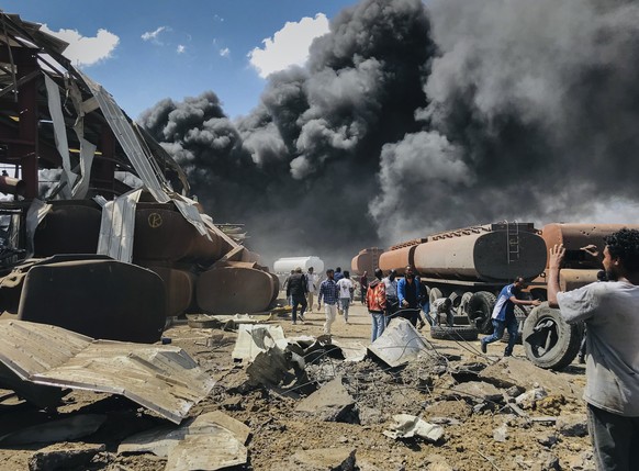 FILE - People are seen in front of clouds of black smoke from fires in the aftermath at the scene of an airstrike in Mekele, the capital of the Tigray region of northern Ethiopia on Oct. 20, 2021. A y ...