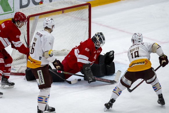 Le gardien lausannois Eetu Laurikainen, gauche, a la lutte pour le puck avec le defenseur genevois Yohann Auvitu, droite, lors du match du championnat suisse de hockey sur glace de National League LNA ...