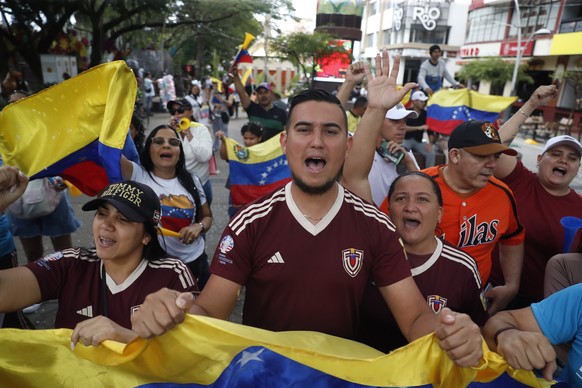 epa12626904 Venezuelan people chant slogans and wave flags during a celebration rally in Cali, Colombia, 04 January 2026. US forces captured Venezuelan President Nicolas Maduro and his wife, Cilia Flo ...