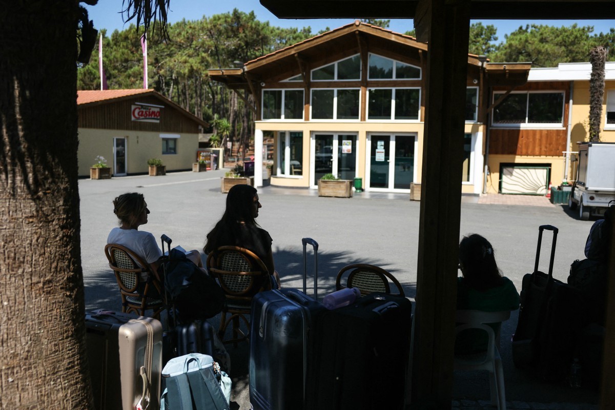 Campers gather with their belongings at the entrance of the Lacanau parking lot following the authorities' decision to evacuate the area due to a wildfire in the Gironde region, in Lacanau, south ...