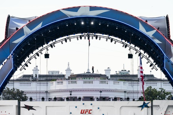 Security at the White House looks through a pair of binoculars during the UFC Fan Fest on the White House Ellipse ahead of Sunday's fight on the South Lawn, Saturday, June 13, 2026, in Washington ...