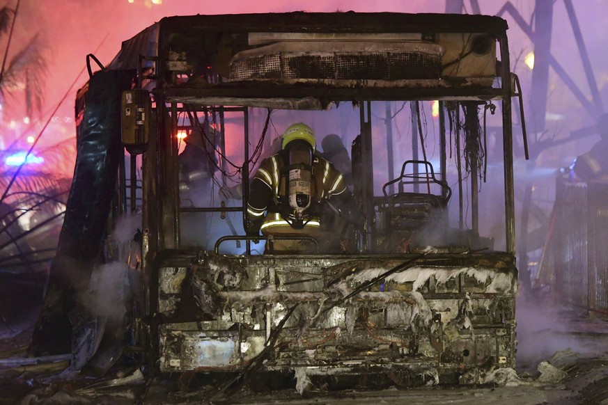 Feuerwehrleute begutachten einen ausgebrannten Bus, der in der Stadt Cholon von einer Rakete aus dem Gaza-Streifen getroffen wurde.