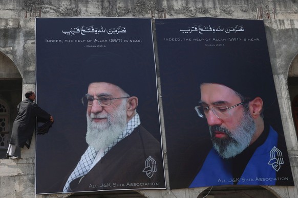 epa12846164 A man cleans a billboard featuring Iran's new Supreme Leader Ayatollah Mojtaba Khamenei (R) and Iran's late Supreme Leader Ayatollah Ruhollah Khomeini (L) on the outskirts of Sri ...
