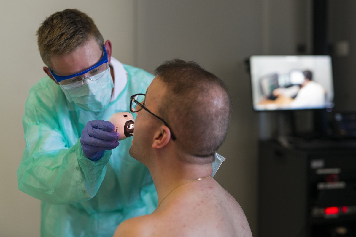 Ein Pflegefachmann untersucht in einer gestellten Praesentation den Rachen eines Patienten, die Daten der Untersuchung werden dank des Diagnosekoffers, der die vernetzten medizinischen Geraete enthael ...