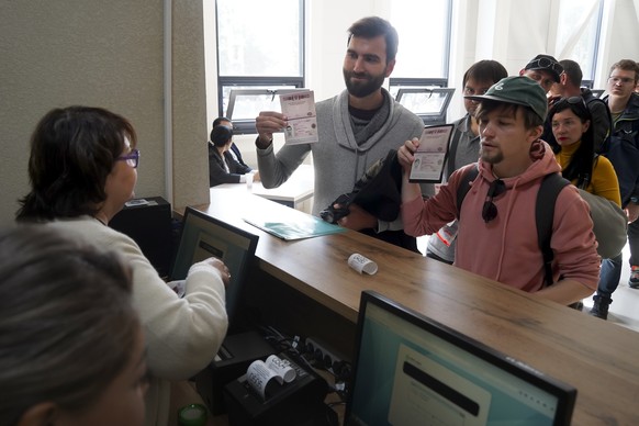 Russians show their passports as they lineup to get Kazakhstan&#039;s a Personal Identification Number (INN) in a public service center in Almaty, Kazakhstan, Monday, Oct. 3, 2022. Kazakhstan, togethe ...