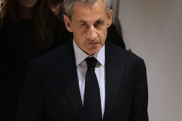 FILE- Former French President Nicolas Sarkozy leaves after a Paris court sentenced him to 5 years after finding him guilty of criminal conspiracy in an alleged scheme to finance his 2007 campaign with ...