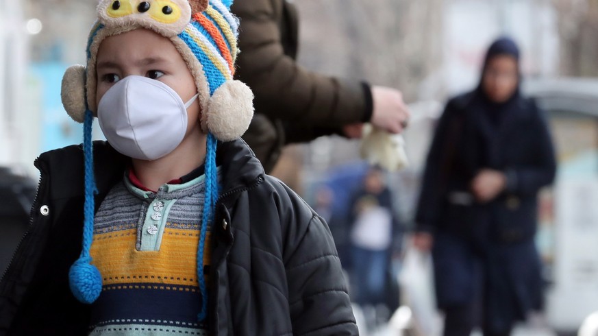 epa08250952 An Iranian child wearing face mask walks on a street of Tehran, Iran, 26 February 2020. According to the Ministry of Health, 139 people diagnosed with the Covid-19 coronavirus and 19 peopl ...