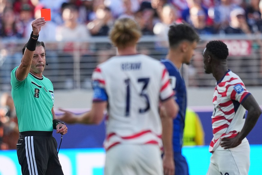Referee Raphael Claus of Brazil shows a red card to United States' Folarin Balogun, right, during the World Cup round of 32 soccer match between the United States and Bosnia in Santa Clara, Calif ...