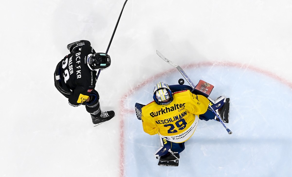 Samuel Walser (HCFG), gauche, lutte pour le puck avec le gardien Sandro Aeschlimann (HCD), droite, lors du quatrieme match de la finale des play-offs du championnat suisse de hockey sur glace de Natio ...