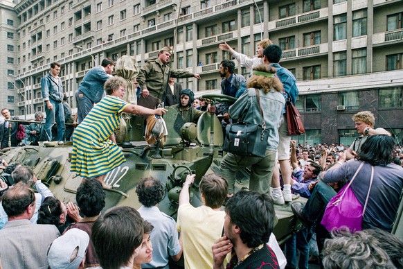 FILE - In this Monday, Aug. 19, 1991 file photo, a crowd gathers around a personnel carrier as some people climb aboard the vehicle and try to block its advance near Red Square in downtown Moscow, Rus ...