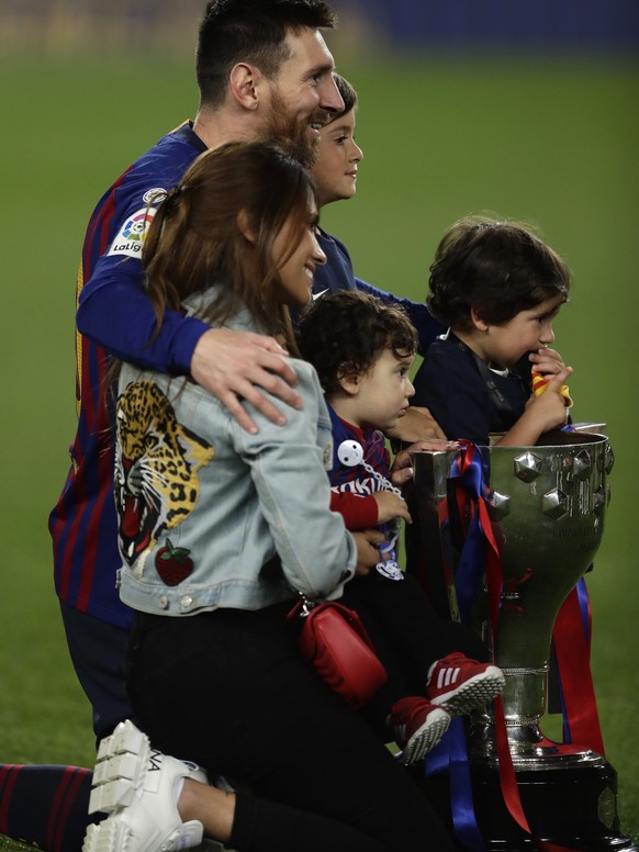 Barcelona forward Lionel Messi, with his family, pose with the trophy after winning the Spanish League title, at the end of the Spanish La Liga soccer match between FC Barcelona and Levante at the Cam ...