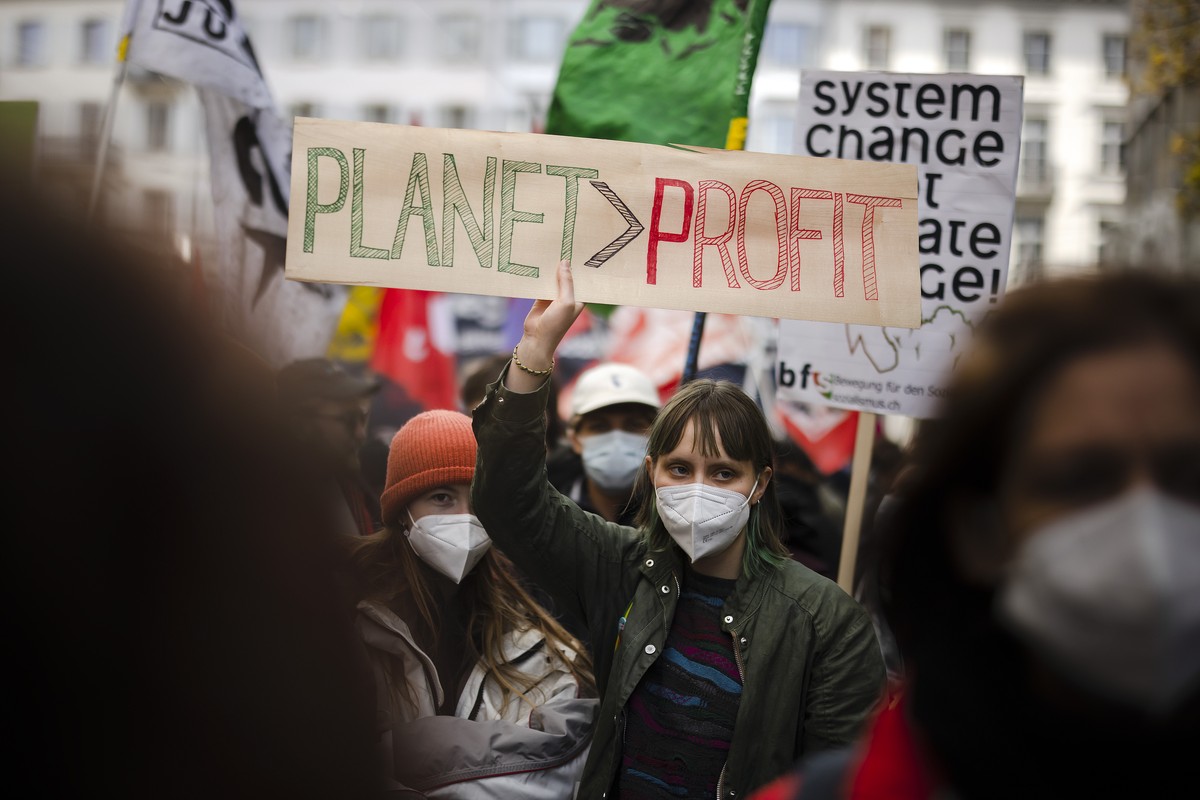A woman holding a placard reading "Planet Profit" attends a climate strike rally calling for work hours to be reduced, on the Muensterhof square in Zurich, Switzerland, on Saturday, April 9, ...