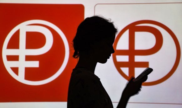 epa10801433 A woman stands in front of logos of Russian digital rubles in Moscow, Russia, 15 August 2023. The Central Bank of Russia will begin testing real digital rubles on August 15, 2023. At the f ...