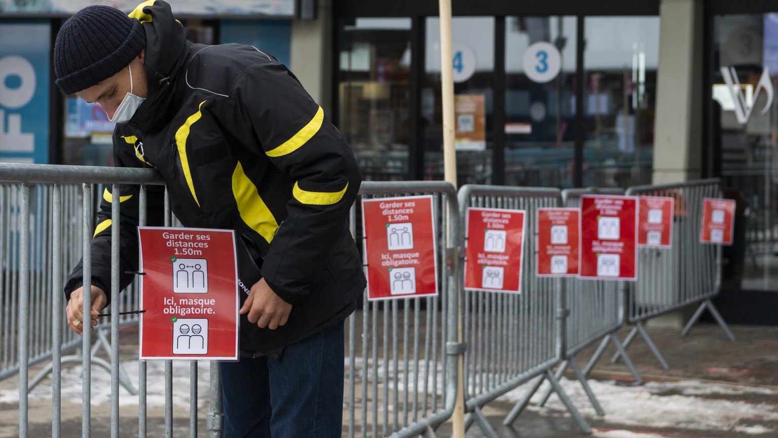 Un employe de Televerbier installe une affiche de la station de ski de Verbier informant de distanciations sociales pour les skieurs au depart des telecabines a Medran lors de la crise du Coronavirus  ...