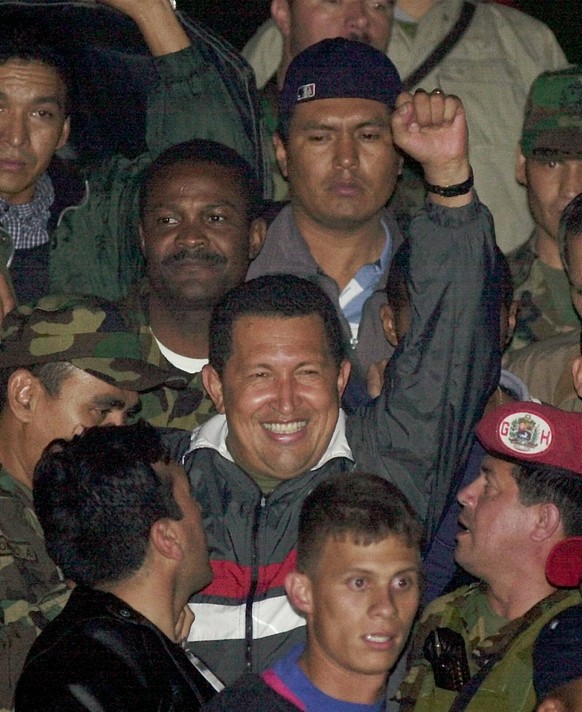 FILE - In this April 14, 2002 file photo, Venezuela&#039;s President Hugo Chavez gestures to supporters as he arrives to Miraflores presidential palace after being freed by his military captors two da ...