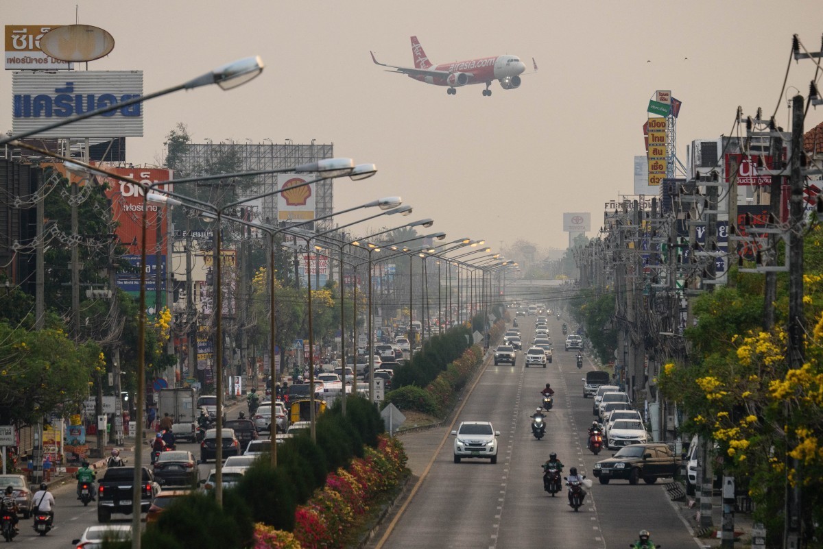 A passenger plane prepares to land at the airport as commuters drive on the road below on a heavily polluted day in Chiang Mai on April 2, 2026. Seasonal agricultural burning, forest fires and weather ...