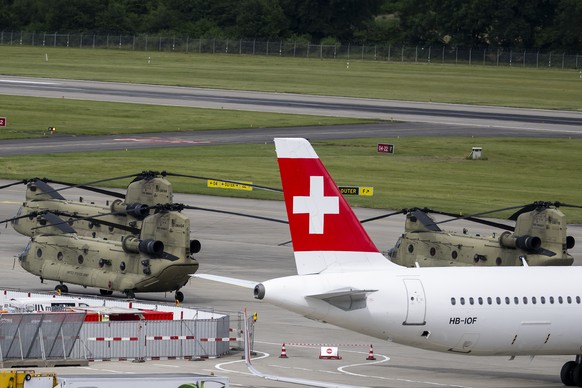 epa13029939 A Swiss airline plane passes in front of American CH-47 Chinook helicopters of the US Army parked on the tarmac of Geneva Airport (Cointrin), against the backdrop of the G7 summit in nearb ...