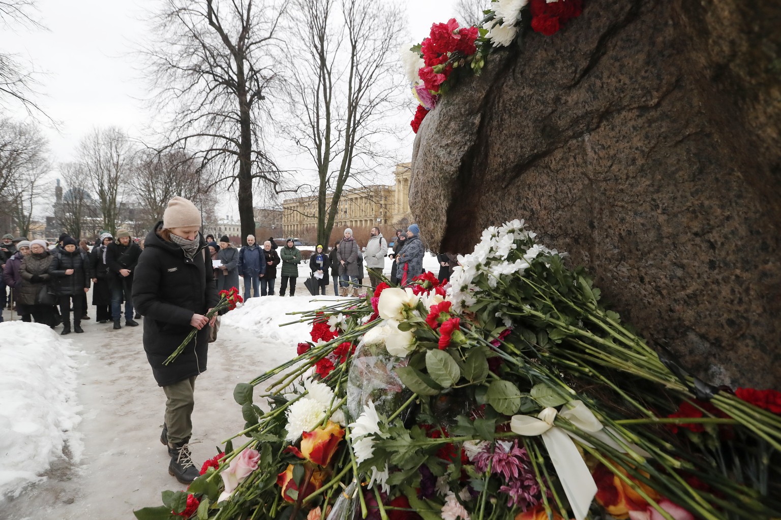 epa11160501 People lay flowers and light candles next to the photo of Russian late opposition leader Alexei Navalny during a vigil following his death, near the memorial to political prisoners in St.  ...