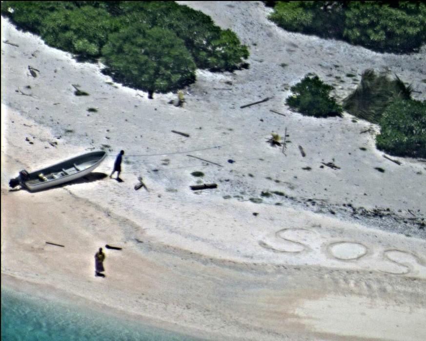 epa05511628 A handout photograph made available on 27 August 2016 by the US Navy showing a pair of stranded mariners signaling for help by writing &#039;SOS&#039; in the sand as a US Navy P-8A Poseido ...