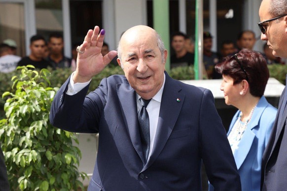 epa11591258 A handout picture provided by the Algerian Presidency Press Service shows Algerian President, Abdelmadjid Tebboune (L), reacting outside of a polling station during the Presidential electi ...