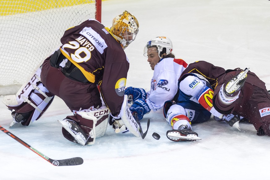 Le joueur zurichois, Roman Wick, centre, a la lutte pour le puck avec le joueur genevois, Jonathan Mercier, droite, devant le gardien genevois, Robert Mayer, gauche lors du match du championnat suisse ...