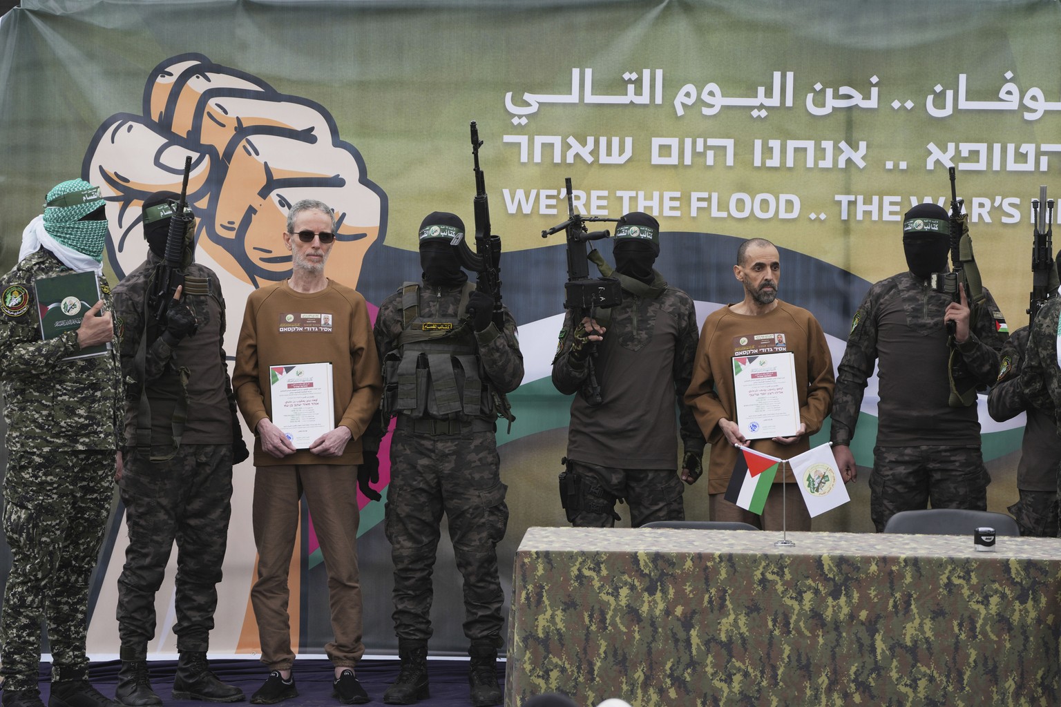 Israeli captives, Ohad Ben Ami, left, and Eli Sharabi, right, who have been held hostage by Hamas in Gaza since October 7, 2023, are escorted by Hamas fighters before being handed over to the Red Cros ...