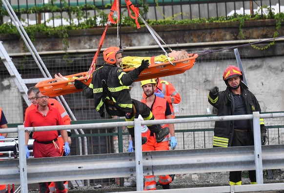 Rescuers recover an injured person after the Morandi highway bridge collapsed in Genoa, northern Italy, Tuesday, Aug. 14, 2018. A large section of the bridge collapsed over an industrial area in the I ...