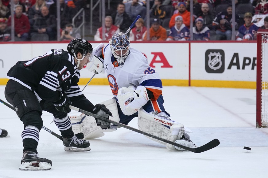 New Jersey Devils&#039; Nico Hischier, left, tries to shoot on New York Islanders goaltender Cory Schneider during the third period of an NHL hockey game in Newark, N.J., Sunday, April 3, 2022. The Is ...