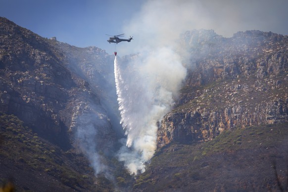epa09146849 A helicopter battles a blaze on the slopes of the world heritage site Table Mountain National Park in Cape Town, South Africa, 20 April 2021. A bushfire has been burning for three days on  ...