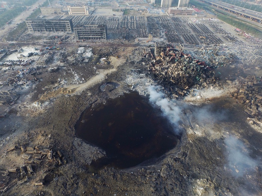 epaselect epa04884801 An aerial view of a large hole in the ground in the aftermath of a huge explosion that rocked the port city of Tianjin, China, 15 August 2015. Explosions and a fireball at a chem ...